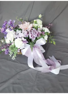 Primer plano detallado de un ramo de flores artificiales con elegante cinta y lazo.