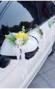 Artificial wedding car flower decoration with white bow and yellow roses for ceremony.