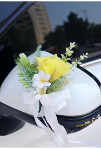 Detailed close-up of artificial wedding car mirror flower decoration with yellow and white blooms.