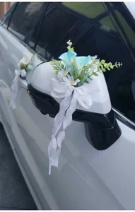 Wedding car artificial flower decoration with blue floral elements and white bow for rearview mirror.