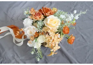 Europaischer oranger kunstlicher Brautstrau mit Rosen und Bandern fur Hochzeitsfotos.