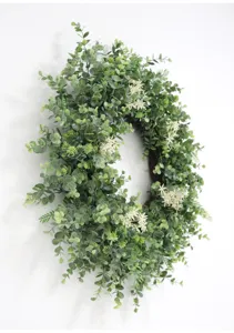Detailed view of artificial eucalyptus wreath with green leaves and white flowers for indoor decor.