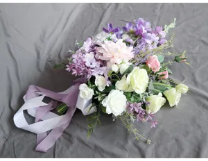 Detalle de ramo de novia artificial con rosas blancas rosas y hortensias moradas cintas.
