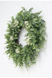 Close-up detail of artificial eucalyptus wreath with white flowers for home decor styling.