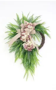 Artificial greenery wreath detail with pink hydrangea and burlap bow for home wall decor.