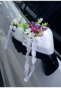 Wedding car artificial flower decoration detail showing purple calla lilies and white bow ribbon.