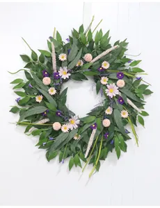 Nahaufnahme Detail des künstlichen Grünblatt Blumenkranzes mit rosafarbenen Gänseblümchen.