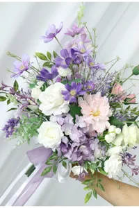Detalle de ramo de flores artificiales, decoración de boda morada y blanca y accesorio de foto.