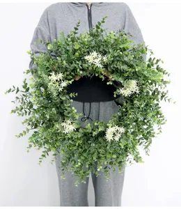 Close up of artificial eucalyptus wreath detail, green leaves with white flowers for home decor.