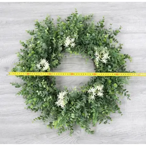 Pastoral style artificial eucalyptus wreath detail with white flowers, home indoor door decor.