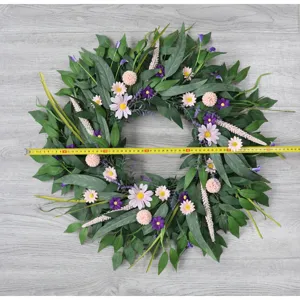 Detailansicht des künstlichen Grünblatt- und Gänseblümchen-Kranzes, ideal für die Wanddeko.