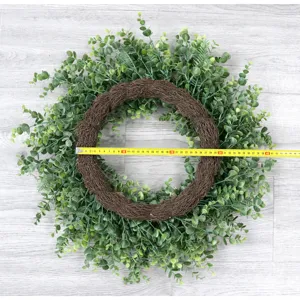 Artificial eucalyptus wreath detail showing green leaves on brown twig base with size measure.