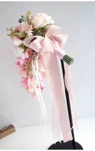 Gedetailleerd uitzicht van het kunstmatige trapsgewijze roze bruidsboeket met chiffon lintdecoratie.