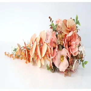 Detailed view of artificial orchid and rose wedding bouquet arrangement in peach and pink tones.