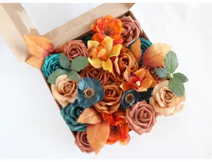 Primer plano de rosas y orquídeas artificiales en tonos otoñales en caja para manualidades.