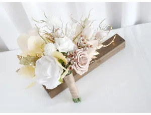 Nahaufnahme des Hochzeits-Brautstraußes mit künstlichen weißen Rosen und Goldglitter.