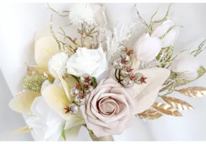 Nahaufnahme Detail des künstlichen Hochzeitsbrautstrausses mit cremeweissen Rosen und Goldglitter.