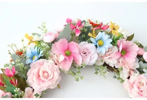 Detaillierte Nahaufnahme des bunten künstlichen Blumenkranzes mit rosa Rosen und Blättern.