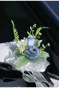 Detail shot of artificial blue rose car mirror flower with elegant sheer ribbon bow, wedding decor.