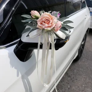 Wedding car mirror decoration with pink artificial roses and elegant white ribbons for big day.