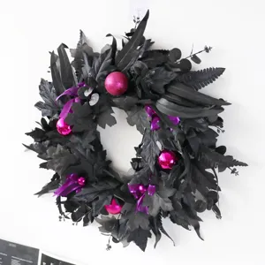 Black artificial maple leaf wreath with magenta ornaments for Halloween door decor.