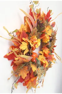 Autumn artificial maple leaf wreath detail featuring vibrant foliage and pumpkins for holiday decor.