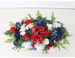 Nahaufnahme Detail künstliche rote weiße blaue Seidenblumen Gesteck mit grünen Farnblättern.