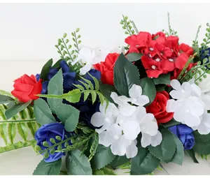 Nahaufnahme von künstlichen rot-weiß-blauen Seidenblumenarrangements mit grünen Blättern.