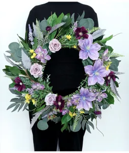 Detailansicht des künstlichen Blumenkranzes mit lila Rosen und Eukalyptusblättern für Wanddekor.