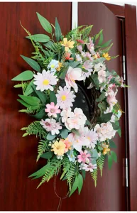 Detailaufnahme eines künstlichen Frühlings-Blumenkranzes an einer Holztür für die Dekoration.