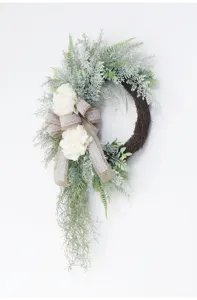 Detailed view of artificial green foliage wreath with white peony flowers and burlap ribbon.