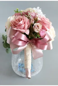 Close-up detail shot of artificial pink and white rose bridal bouquet with satin bow.