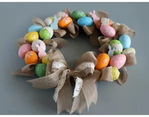 Easter wreath detail showing colorful decorative eggs, burlap bow and cute bunny silhouettes.