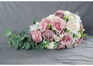 Artificial cascade wedding bouquet detail featuring pink roses and green leaves.