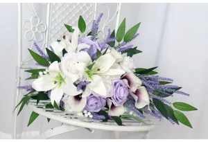 Close-up detail of artificial wedding bouquet featuring white lilies and purple roses.