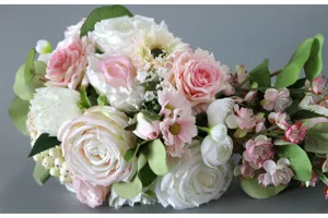 Gros plan détaillé d'un bouquet de mariée artificiel, roses roses et blanches avec des feuilles.