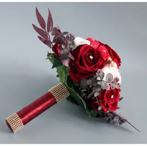 Detailed view of the artificial bridal wedding bouquet featuring red and white roses with rhinestones.