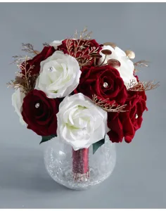 Dettaglio di bouquet da sposa artificiale con rose rosse e bianche e vaso di vetro.