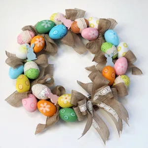 Easter wreath door hanging decoration with colorful eggs, burlap bows and cute wooden rabbits.