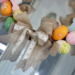 Easter wreath with burlap bow, colorful eggs, and wooden rabbit for holiday door decoration.