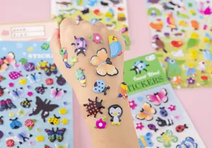 Close-up detail view of colorful 3D puffy cartoon insect and animal stickers on child arm