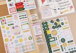 Gedetailleerde opname van decoratieve planner-stickervellen en kleurrijke memostickers op notitieboek.