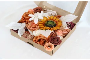 Detalle de rosas artificiales y girasoles de otoño en una caja de regalo decorativa.