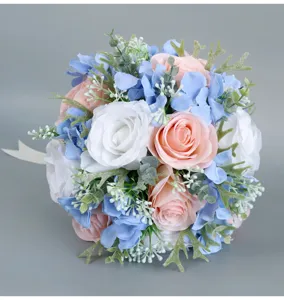 Close-up detail of artificial bridal wedding bouquet with pink blue roses and greenery.