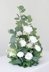 Künstliches Blumenarrangement für Hochzeitstischdekoration mit weißen Rosen und grünen Blättern.