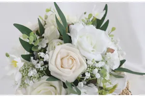 Nahaufnahme des eleganten künstlichen Hochzeits-Brautstraußes mit weißen Rosen und grünen Blättern.