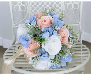 Detail shot of artificial wedding flower bouquet featuring pink and white roses with blue hydrangea.