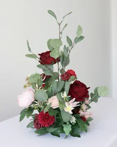Nahaufnahme des künstlichen Blumen-Mittelstücks mit roten Rosen und Eukalyptusblättern.