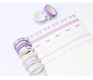 Close-up detail of purple washi tape rolls featuring floral and geometric patterns for journaling.