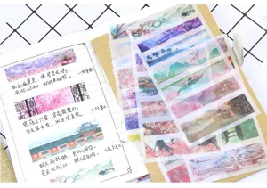 Dettaglio degli adesivi washi con paesaggi cinesi antichi disposti sopra un taccuino.